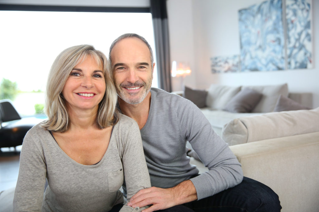 couple with grey color outfit sitting on couch is smiling